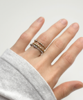 Hand wearing a stack of gold rings on a plain background