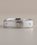 Silver ring with embedded diamonds on a beige background
