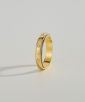 Gold ring with small diamonds on a light gray background