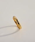 Gold ring with small diamonds on a light gray background