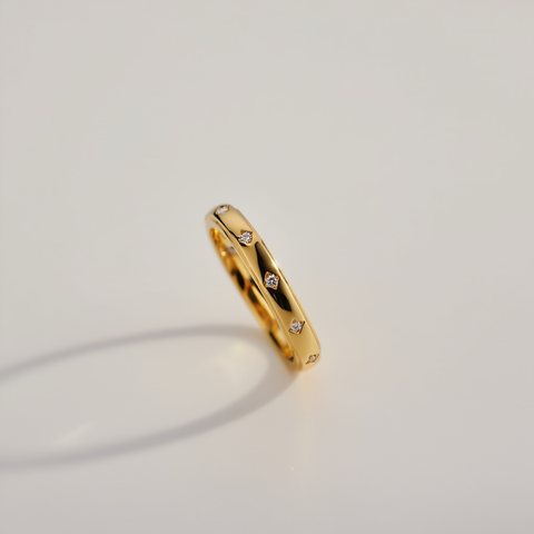 Gold ring with small diamonds on a light gray background