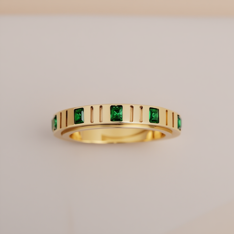 Gold ring with green gemstones on a light gray background