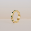 Gold anxiety ring with emerald on a beige background 