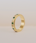 Gold anxiety ring with emerald on a beige background 