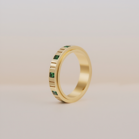 Gold anxiety ring with emerald on a beige background 