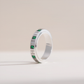Silver ring with green gemstones on a light beige background