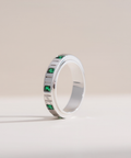 Silver ring with green gemstones on a light beige background