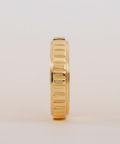 Gold ring with a textured band on a light beige background