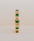 Gold ring with green gemstones on a beige background