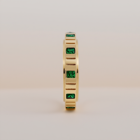 Gold ring with green gemstones on a beige background