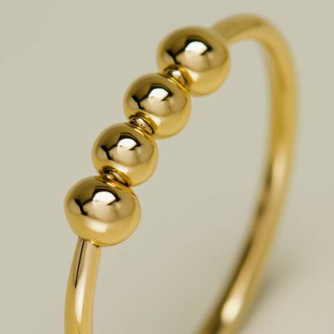 Gold ring with three beads on a light gray background