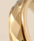 Gold ring with a textured band on a light beige background