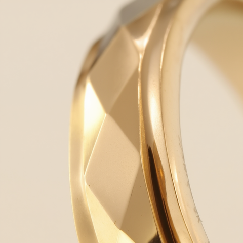 Gold ring with a textured band on a light beige background