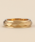 Gold ring with a textured band on a beige background