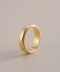 Gold ring with embedded diamonds on a beige background