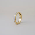 Gold ring with embedded diamonds on a light gray background