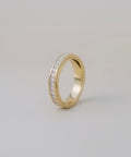 Gold ring with embedded diamonds on a light gray background