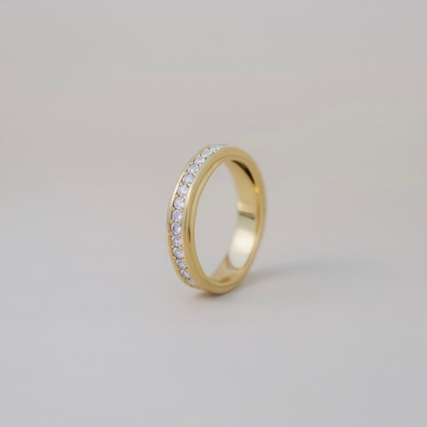 Gold ring with embedded diamonds on a light gray background