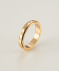 Gold ring with a textured design on a light beige background