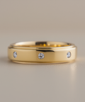 Gold ring with three diamonds on a beige background
