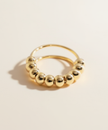 Gold hoop earring with round beads on a beige background