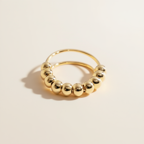 Gold hoop earring with round beads on a beige background