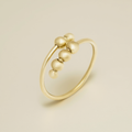 Gold ring with three spherical beads on a beige background