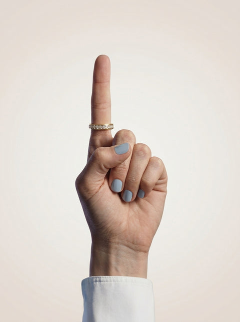 Hand with a gold ring on a beige background