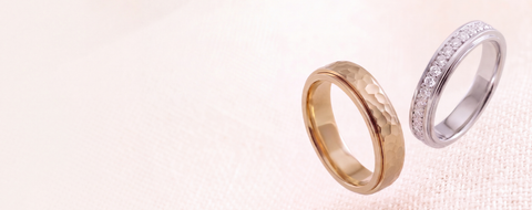 Two gold and silver rings on a light pink background