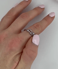 Hand with pink nail polish wearing a silver ring on a white background