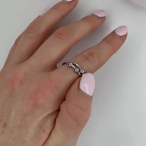 Hand with pink nail polish wearing a silver ring on a white background