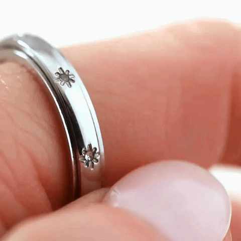 A macro shot of a thumb spinning a fidget ring along their index finger. 
