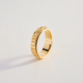 Gold ring with a textured band on a light gray background