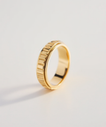 Gold ring with a textured band on a light gray background