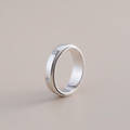 Silver ring with embedded diamonds on a beige background