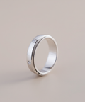 Silver ring with embedded diamonds on a beige background