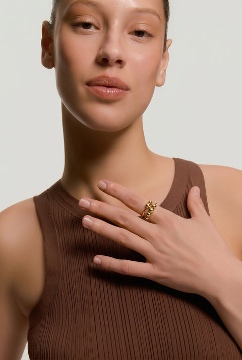 Woman wearing a brown sleeveless top with a plain background