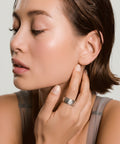 Woman adjusting earring with a plain background