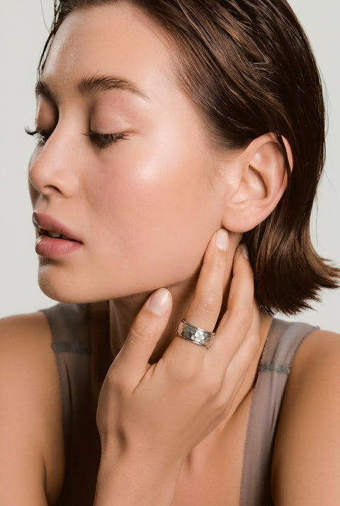 Woman adjusting earring with a plain background