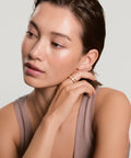 Woman wearing a gold earring against a plain background