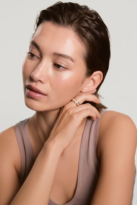Woman wearing a gold earring against a plain background