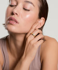 Woman applying cream to her face with a neutral background