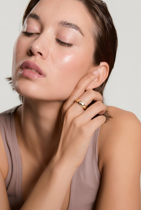 Woman applying cream to her face with a neutral background
