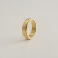 Gold ring with a textured surface on a light beige background