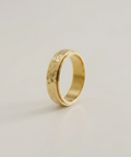 Gold ring with a textured surface on a light beige background