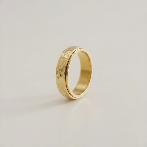 Gold ring with a textured surface on a light beige background