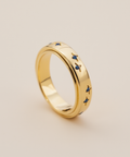 Gold ring with blue gemstones on a beige background