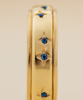 Gold ring with blue gemstones on a beige background