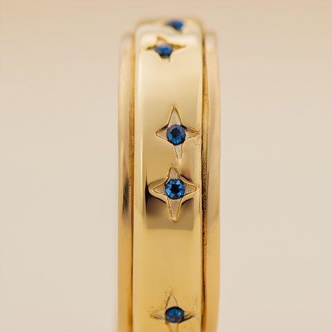 Gold ring with blue gemstones on a beige background