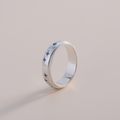 Silver ring with blue butterfly patterns on a light gray background